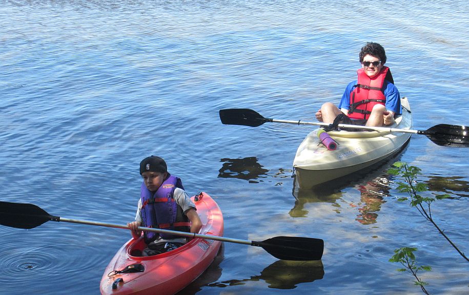 Two boys paddling kayaks across Great Pond